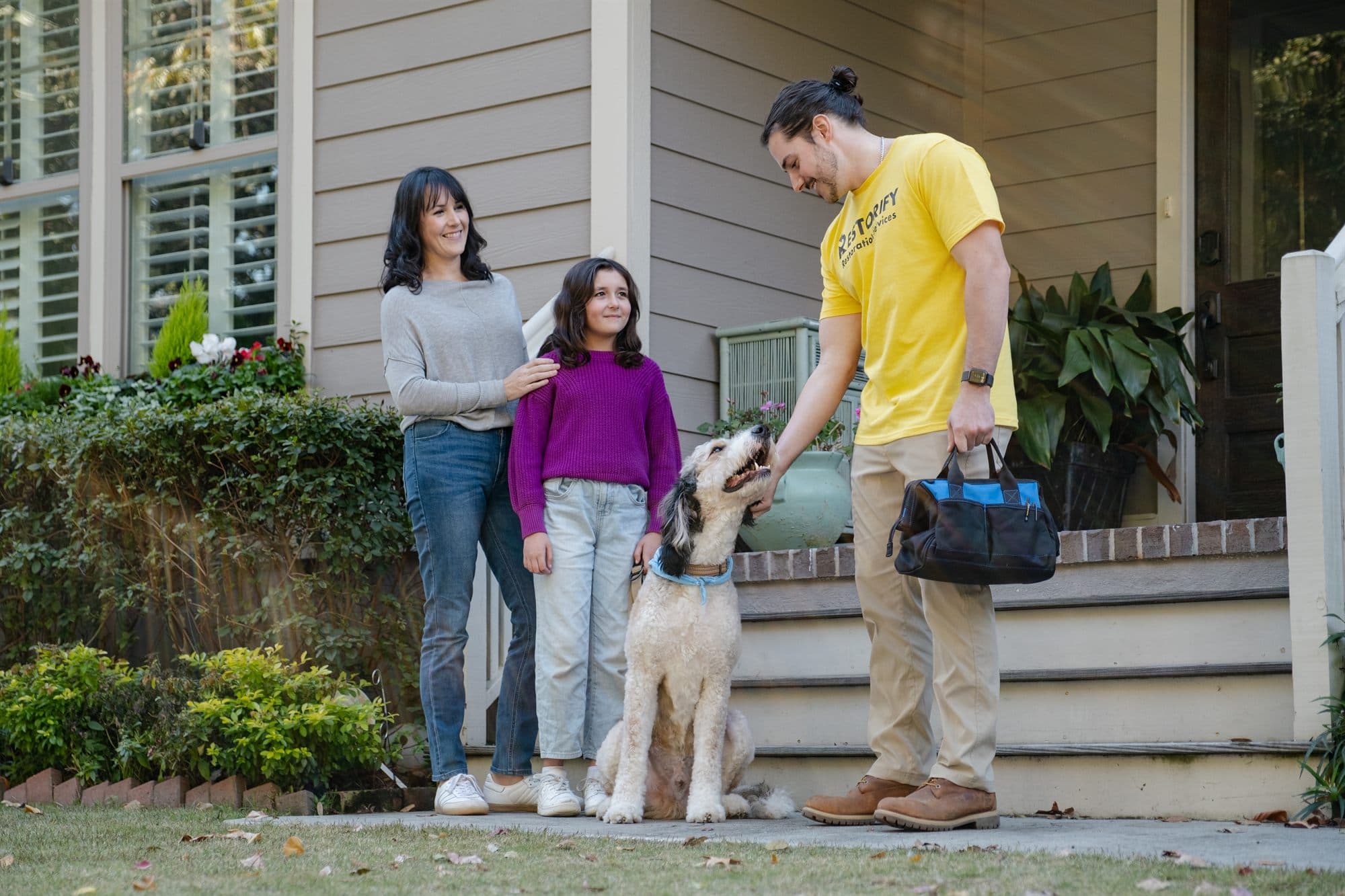 A Restorify technician greeting a Charleston family and their dog at home