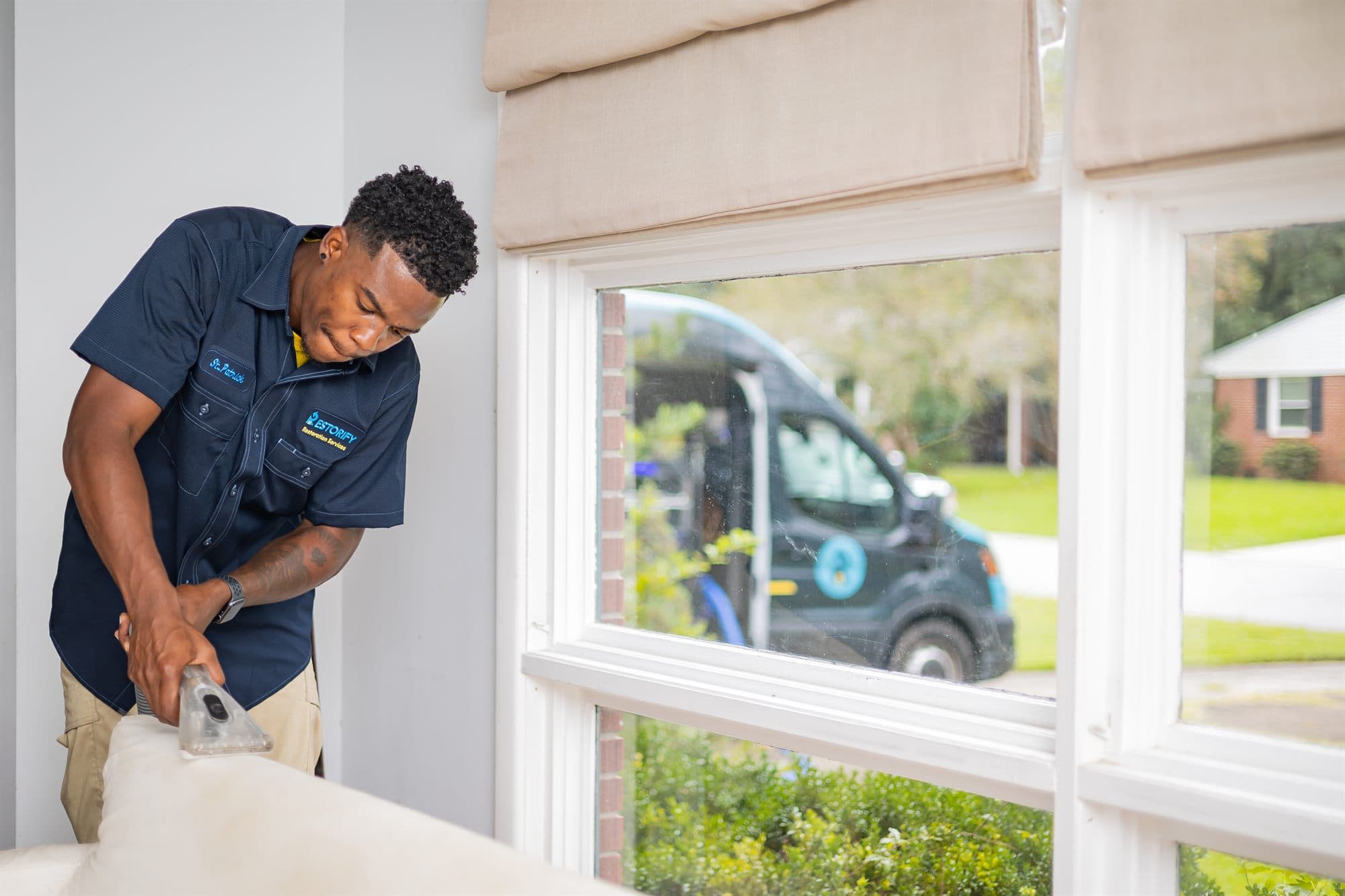 Restorify technician cleaning upholstery, with the branded van outside